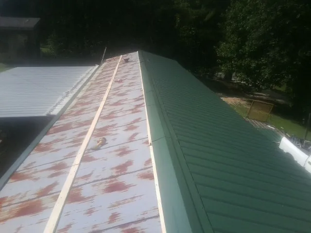 Old rusted panels beside newly installed green metal roofing — Wind Damage Roof Repair by Roofing Brothers in Welaka