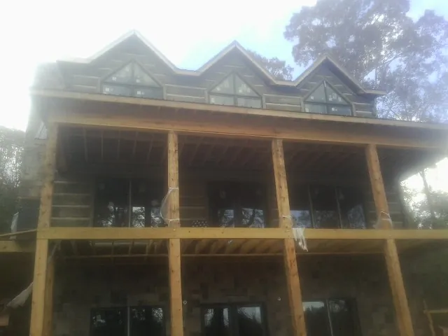 Dormers and porch framing on a large log home under construction — Roof Coating work by our crew in Welaka