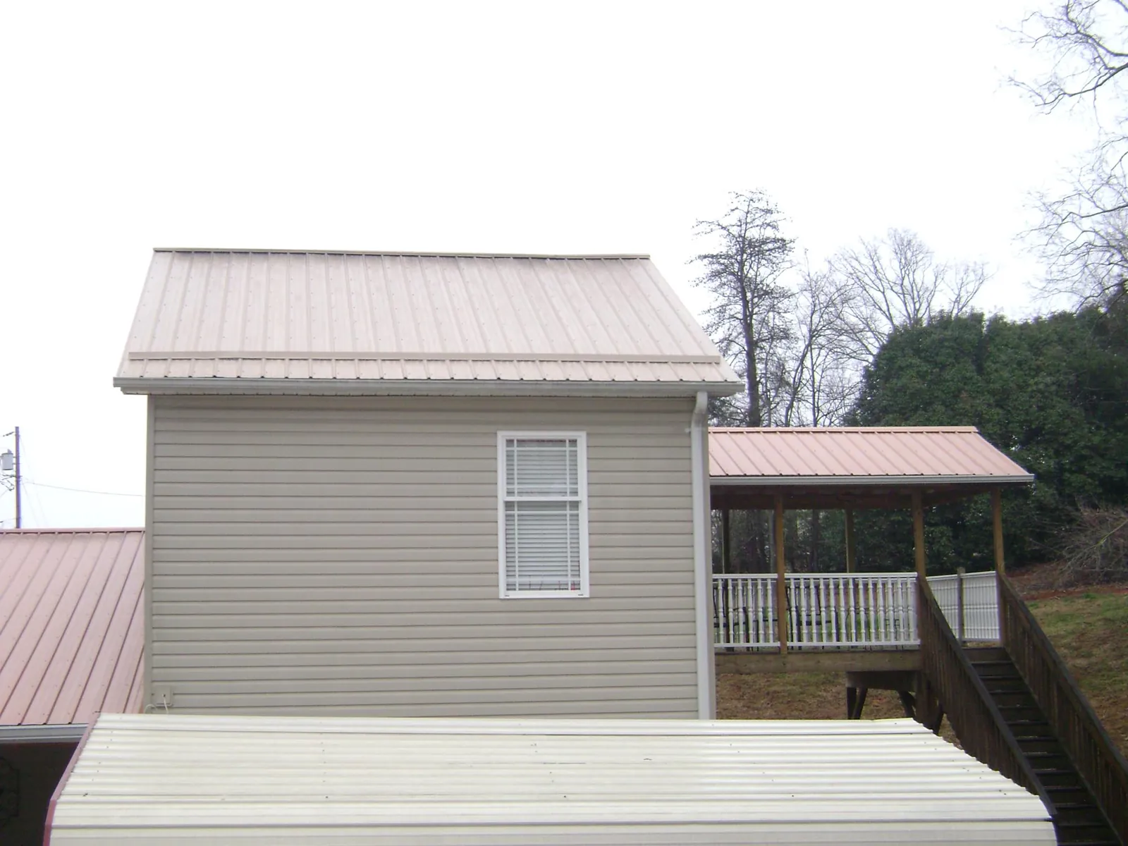 Tan metal roofs on a two story addition and attached porch, from a Roof Replacement job in Welaka